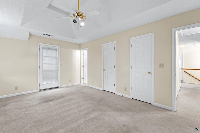 unfurnished bedroom with a textured ceiling, baseboards, attic access, and carpet floors