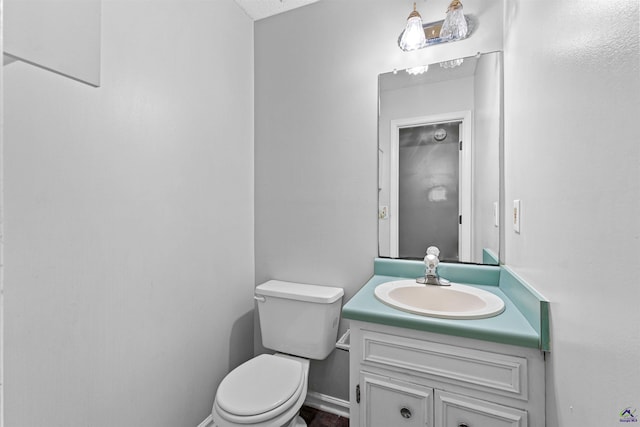 half bathroom with toilet, vanity, and baseboards