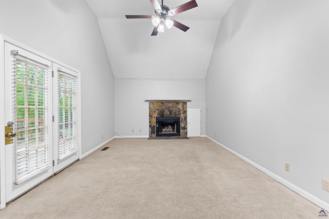 unfurnished living room with carpet flooring, ceiling fan, a stone fireplace, and vaulted ceiling