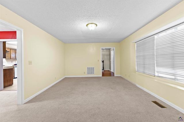 unfurnished room with visible vents, baseboards, light carpet, and a textured ceiling