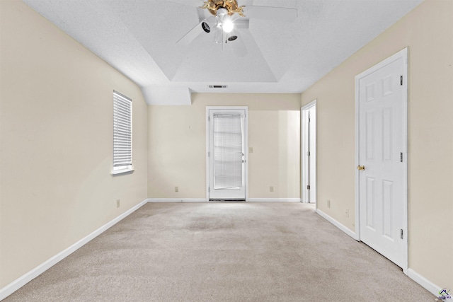 carpeted empty room featuring a textured ceiling, ceiling fan, baseboards, and visible vents