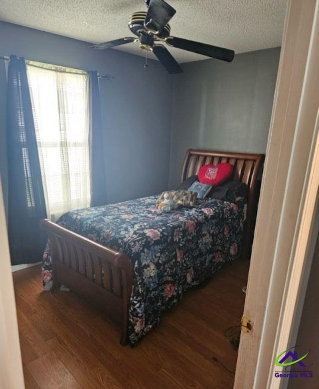 bedroom with wood finished floors, a textured ceiling, and a ceiling fan