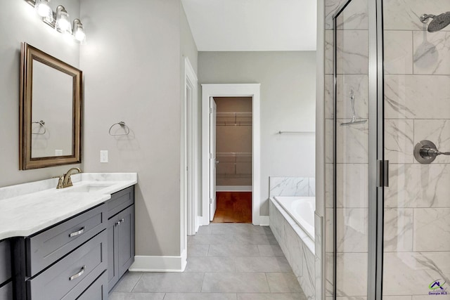 bathroom featuring a garden tub, a shower stall, vanity, a spacious closet, and baseboards