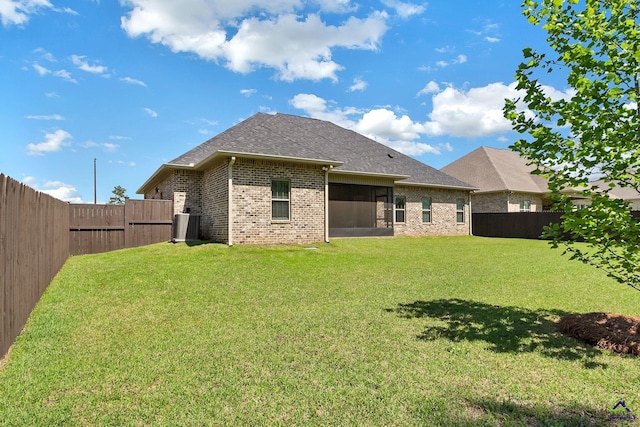 rear view of property featuring a lawn, a shingled roof, a fenced backyard, and brick siding