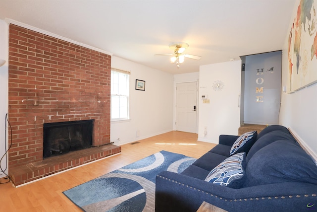 living area featuring visible vents, wood finished floors, ceiling fan, and a brick fireplace