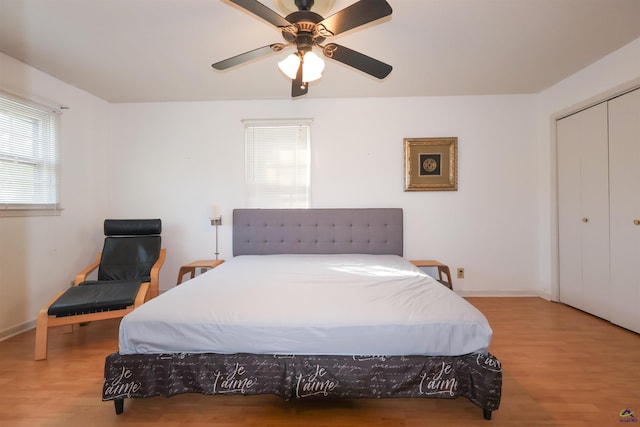 bedroom featuring ceiling fan, a closet, baseboards, and wood finished floors