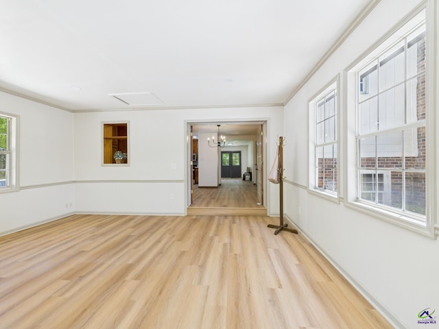 spare room featuring crown molding, light wood finished floors, baseboards, and an inviting chandelier