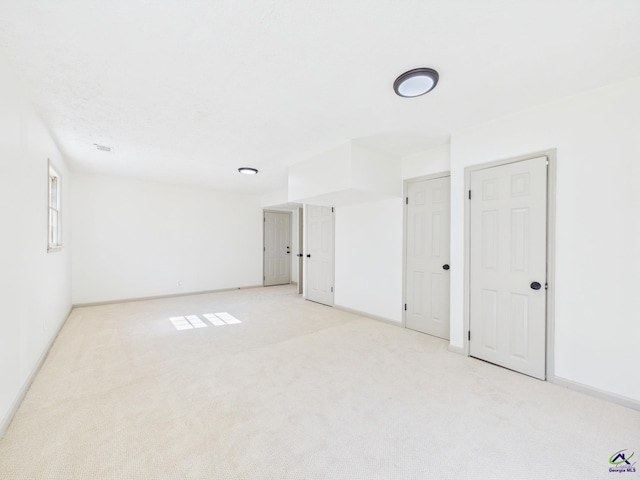 unfurnished room featuring light carpet and baseboards