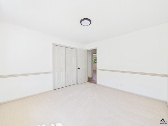 unfurnished bedroom featuring light carpet, a closet, and baseboards