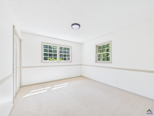 carpeted empty room featuring a wealth of natural light and visible vents