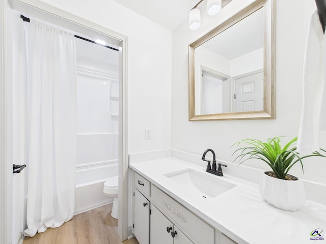 bathroom featuring toilet, shower / bath combo with shower curtain, vanity, and wood finished floors