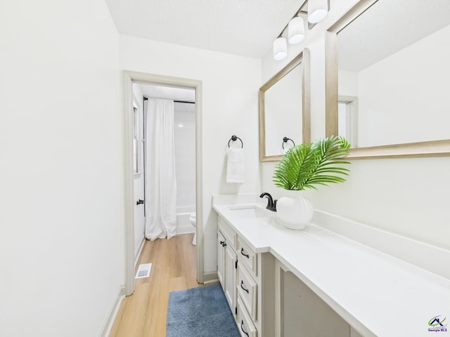 bathroom with vanity, visible vents, toilet, and wood finished floors