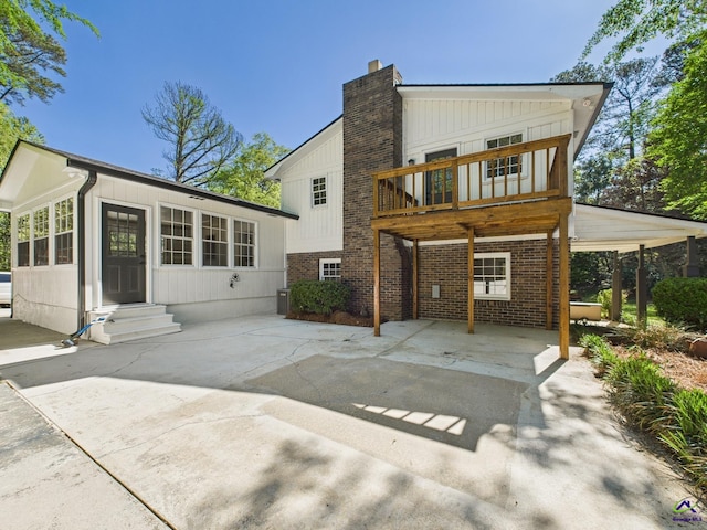 back of property featuring entry steps, board and batten siding, brick siding, and a chimney