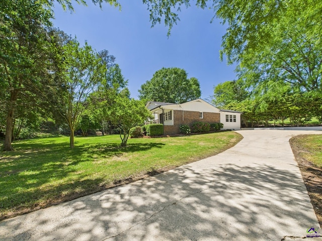 view of front of house featuring concrete driveway, a front lawn, and brick siding