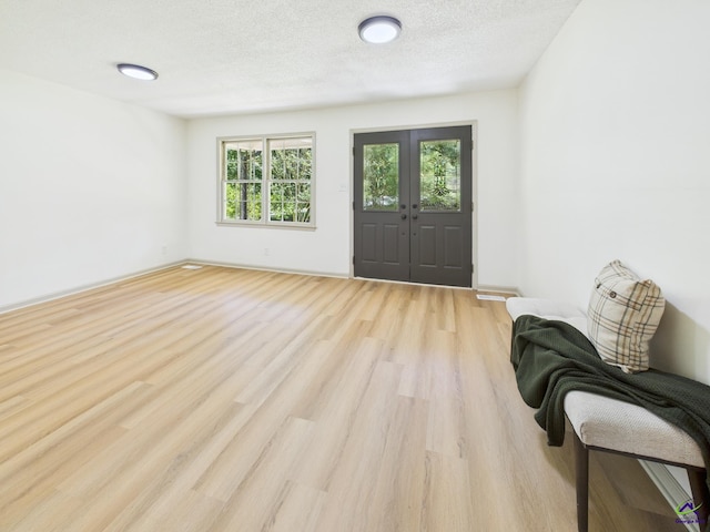 entrance foyer with french doors, a textured ceiling, and wood finished floors