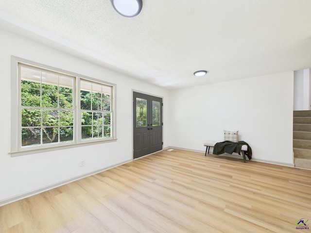 entrance foyer featuring baseboards, a textured ceiling, wood finished floors, and stairs