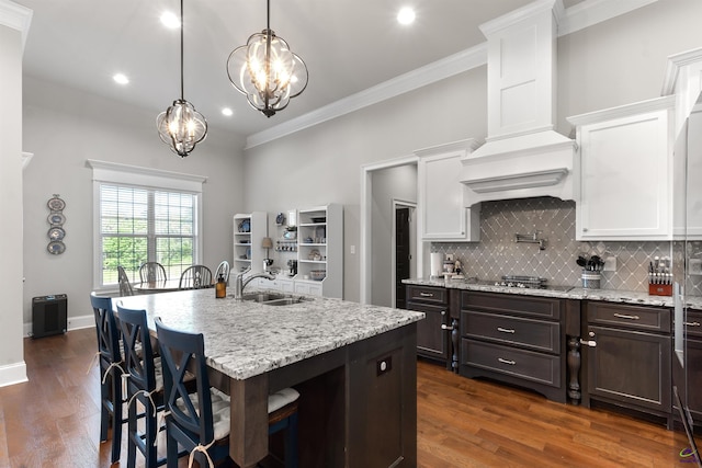 kitchen featuring a chandelier, a sink, ornamental molding, and white cabinets