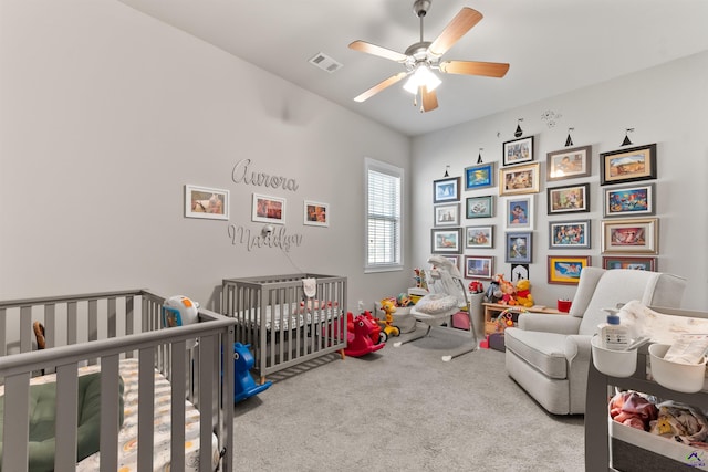 carpeted bedroom with a nursery area, visible vents, and ceiling fan