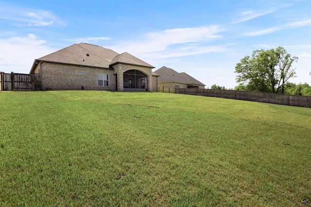 rear view of house with a yard, brick siding, and fence