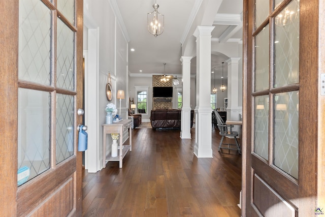 foyer with decorative columns, arched walkways, ornamental molding, dark wood-style flooring, and a notable chandelier