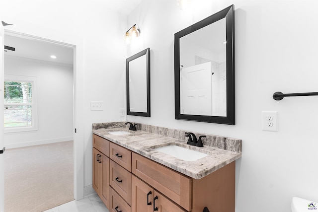 full bath with double vanity, marble look tile flooring, and baseboards
