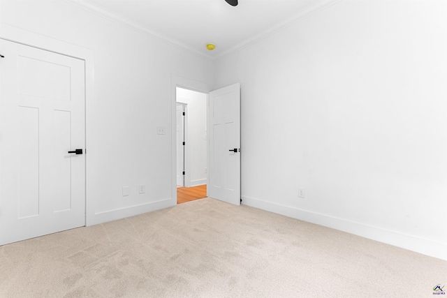 unfurnished bedroom featuring crown molding, carpet floors, baseboards, and ceiling fan