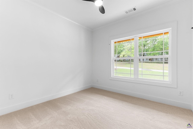 unfurnished room featuring crown molding, light colored carpet, a ceiling fan, healthy amount of natural light, and baseboards