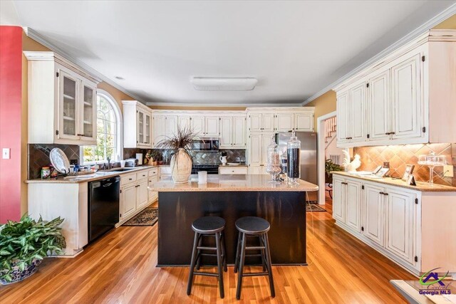 160 Barrington Hall Dr, Macon, GA 31220 - kitchen featuring tasteful backsplash, a center island, light wood-style floors, a kitchen bar, and appliances with stainless steel finishes