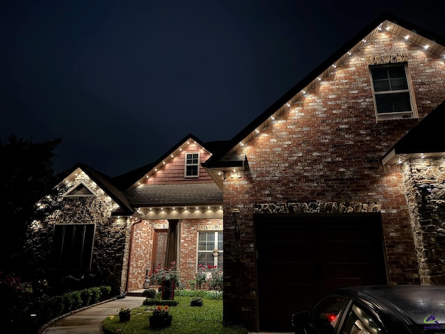 view of front facade featuring an attached garage, a shingled roof, and brick siding