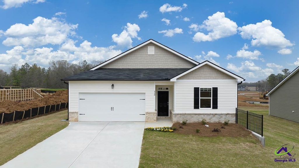 ranch-style home featuring roof with shingles, concrete driveway, fence, an attached garage, and a front yard