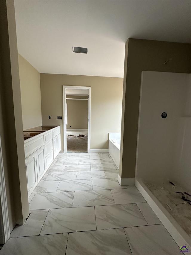full bath with marble look tile flooring, a bath, baseboards, and a shower