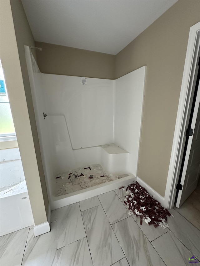 full bath featuring a shower, baseboards, and marble finish floors