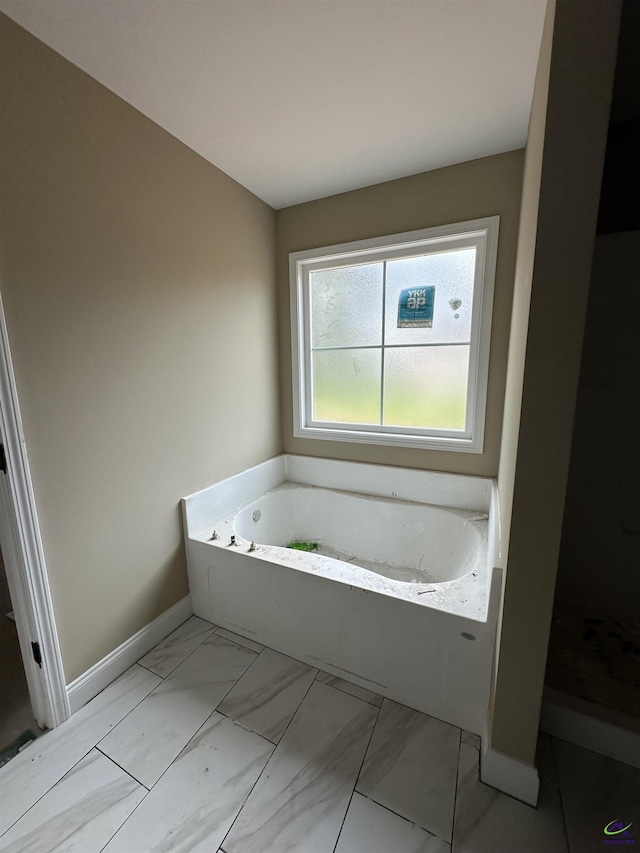 full bathroom with a garden tub, marble finish floors, and baseboards