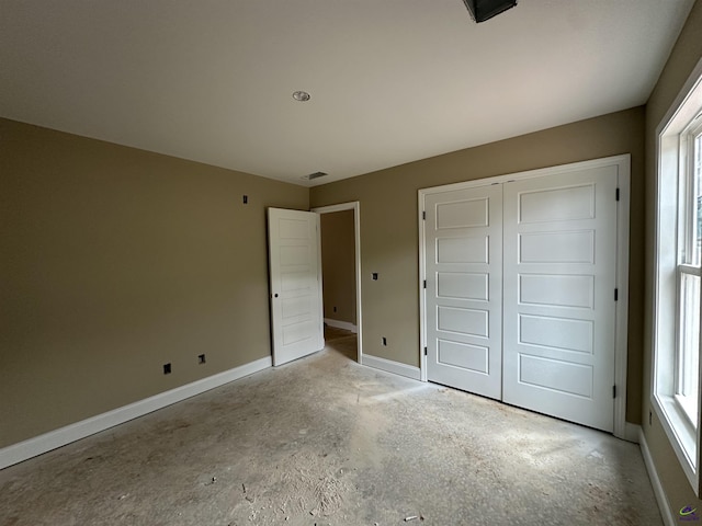 unfurnished bedroom with a closet, baseboards, and multiple windows