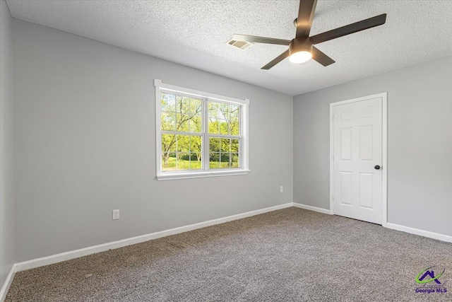 spare room with carpet, a ceiling fan, visible vents, and a textured ceiling