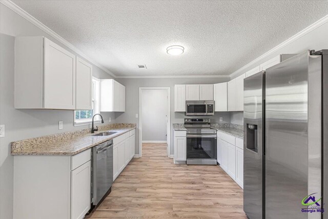 kitchen with ornamental molding, appliances with stainless steel finishes, a sink, and a textured ceiling