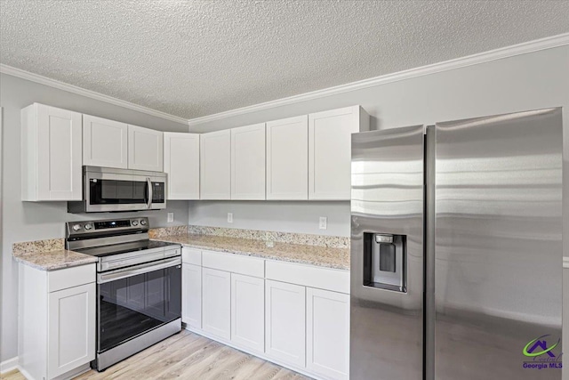 kitchen featuring light wood-type flooring, a textured ceiling, crown molding, and stainless steel appliances