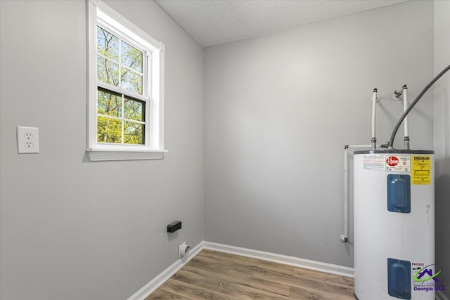 laundry area featuring a textured ceiling, wood finished floors, water heater, baseboards, and laundry area