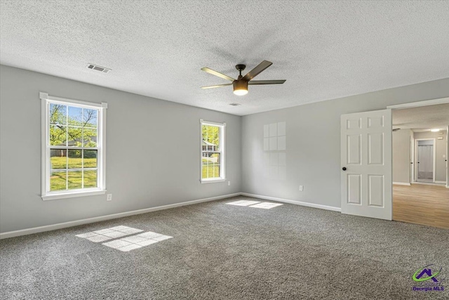 carpeted empty room featuring baseboards, visible vents, a wealth of natural light, and ceiling fan