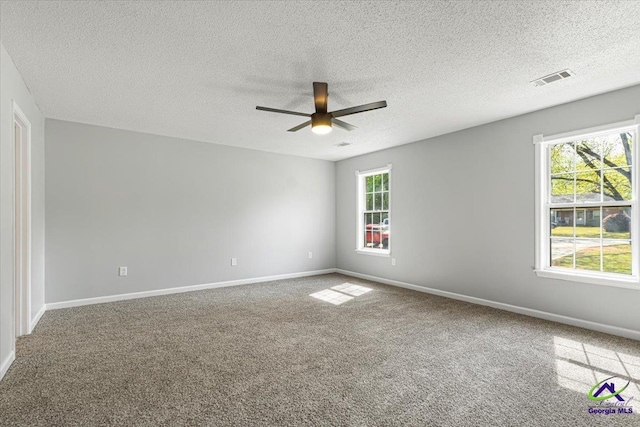carpeted empty room featuring visible vents, baseboards, a textured ceiling, and ceiling fan
