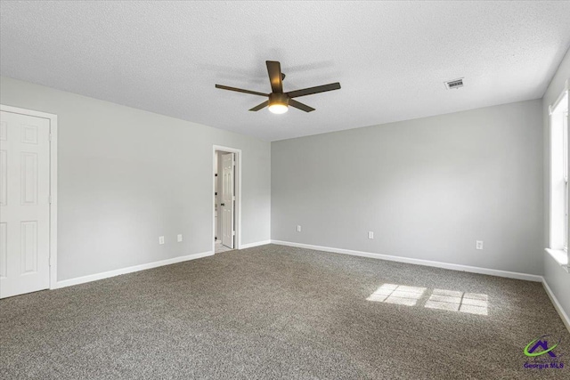 unfurnished room with a textured ceiling, carpet flooring, visible vents, and a ceiling fan