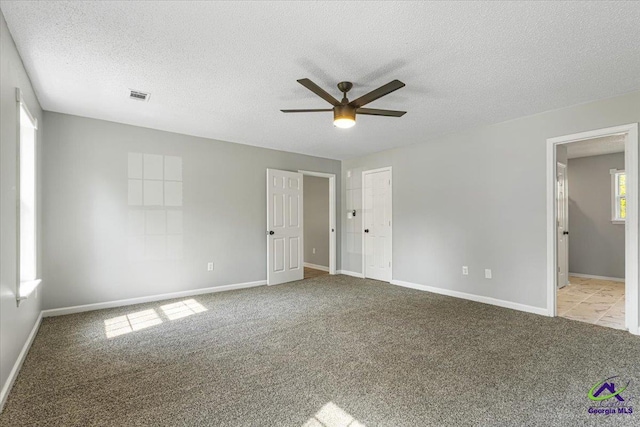 unfurnished bedroom with a textured ceiling, baseboards, visible vents, a ceiling fan, and carpet floors
