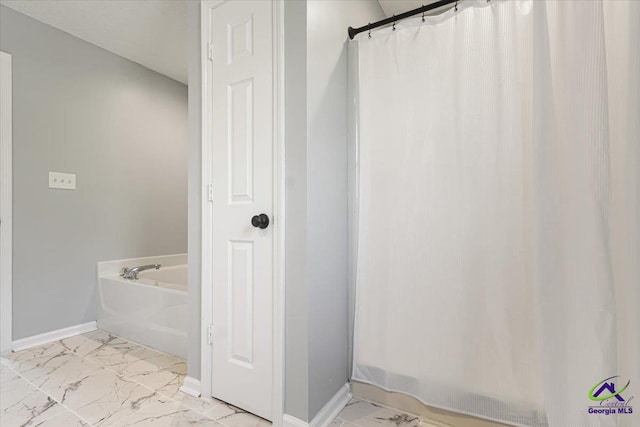 full bath with a garden tub, marble finish floor, and baseboards
