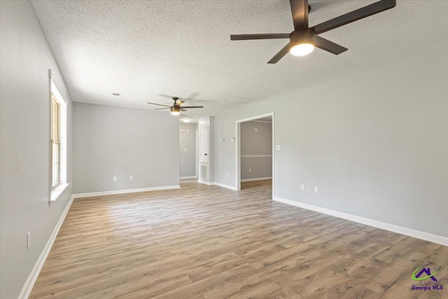 spare room featuring a ceiling fan, baseboards, a textured ceiling, and light wood-style flooring