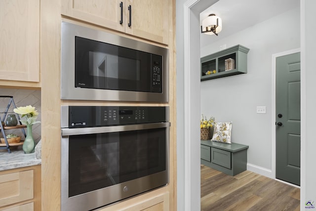 kitchen featuring light brown cabinetry, wood finished floors, appliances with stainless steel finishes, and tasteful backsplash