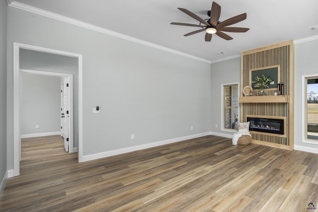 unfurnished living room with a ceiling fan, wood finished floors, a fireplace, baseboards, and ornamental molding