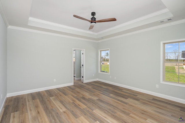 empty room featuring visible vents, a tray ceiling, and wood finished floors