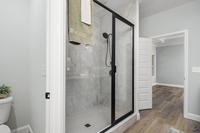 bathroom featuring baseboards, wood finished floors, a shower stall, and toilet