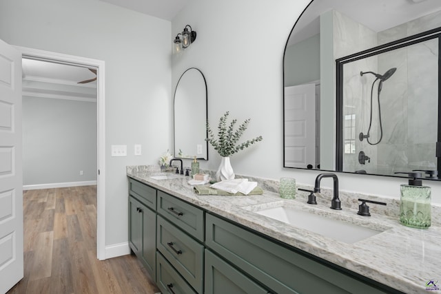 full bath featuring a sink, tiled shower, and double vanity