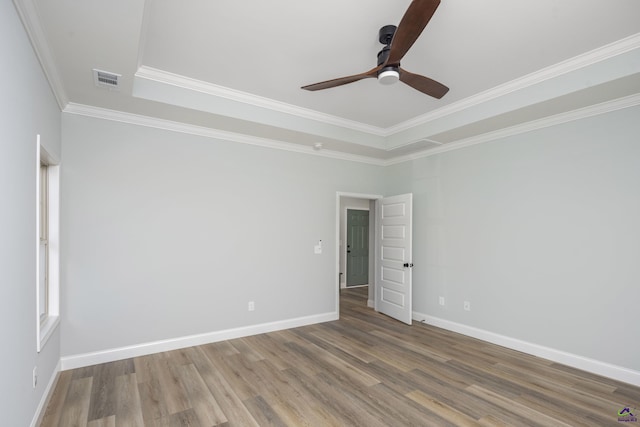 empty room with crown molding, wood finished floors, baseboards, and a ceiling fan